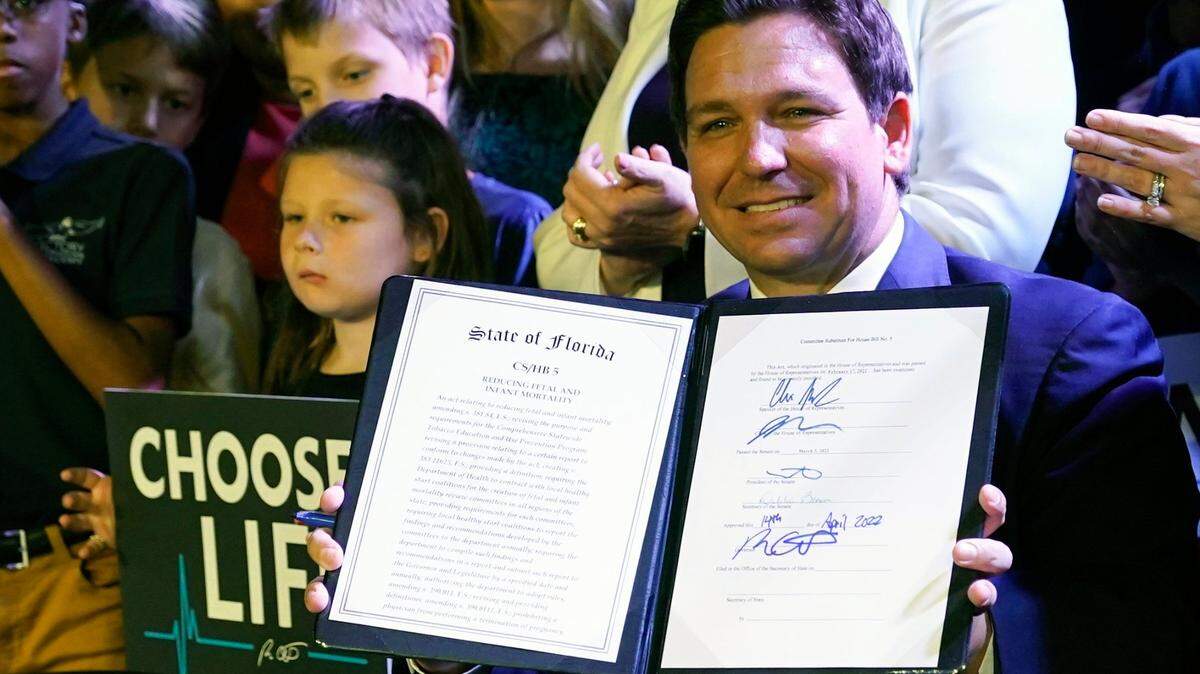 Florida Gov. Ron DeSantis holds up a 15-week abortion ban law after signing it on April 14, 2022, in Kissimmee, Fla.