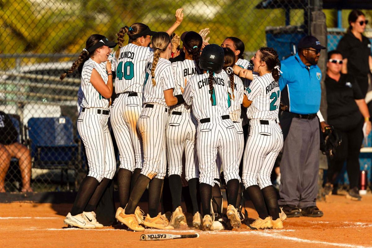 Coral Reef softball players swarm Brianna Fields (88) after she hit a three-run homer during the GMAC softball championship game against Palmetto at South Dade High School on Thursday, April 17, 2025, in Miami, Fla.