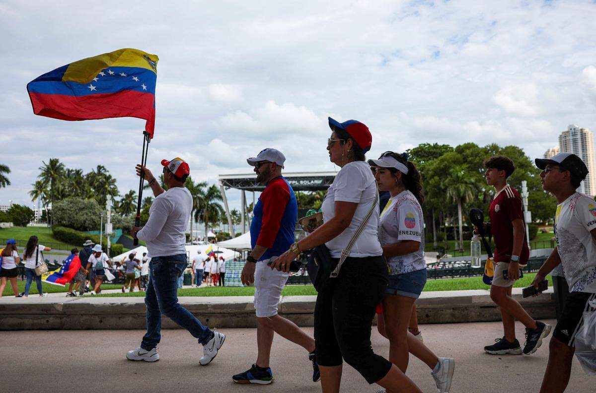 A man waving a Venezuelan flag arrives along with other people at a rally at the FPL Solar Amphitheater Auditorium in downtown Miami.