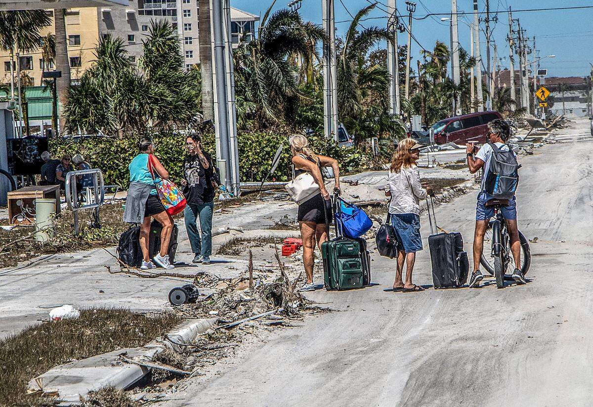 Residents walk along Estero Boulevard with suitcases as they leave Fort Myers Beach and Estero Island, two days after Hurricane Ian hit Florida’s west coast as a Category 4 storm.