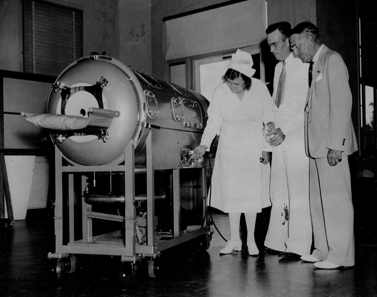 Nurse Mary Corbett shows a new iron lung at Jackson Memorial Hospital, with Bryon C. Hanks, president of FPL, and Chas A. Mells, president of the hospital board.