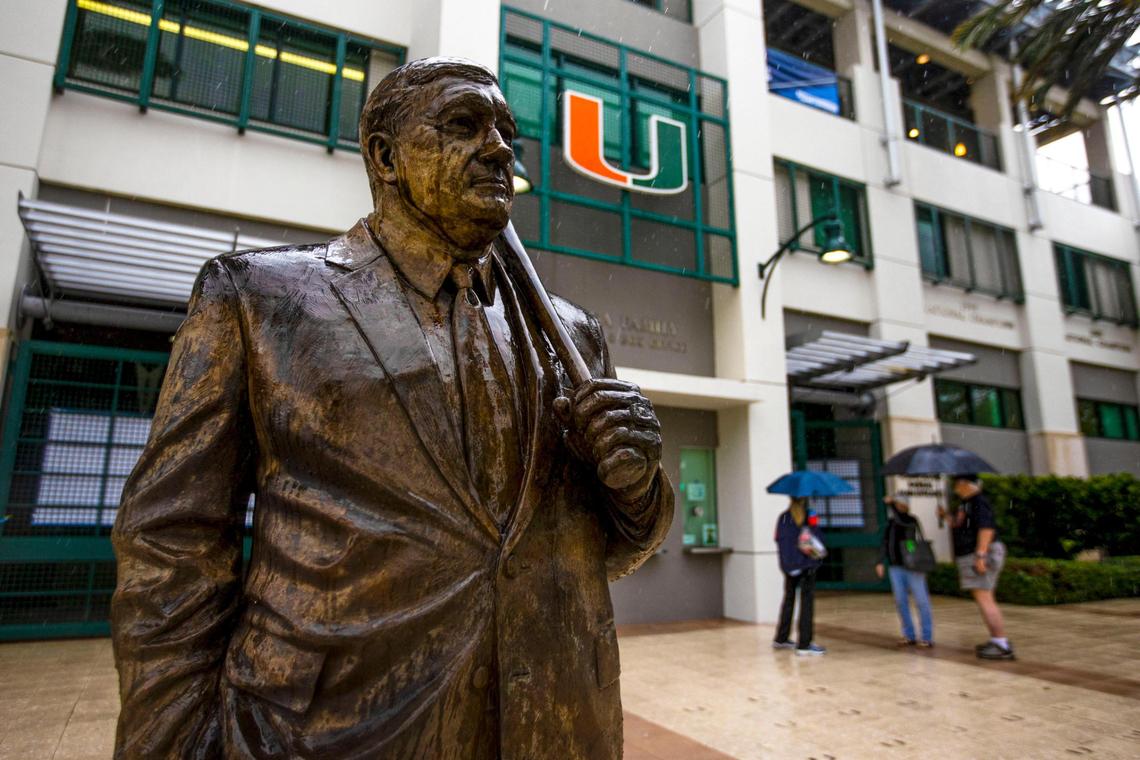 The Ron Fraser statue stands soaked as umbrella toting fans begin their departure after learning the University of Miami baseball team was forced to postpone the first round of the NCAA Division I Baseball Tournament against Canisius College due to rain at Alex Rodriguez Park at Mark Light Field in Coral Gables, Florida, on Friday, June 3, 2022. The Coral Gables Regional has been moved to Saturday, June 4th.