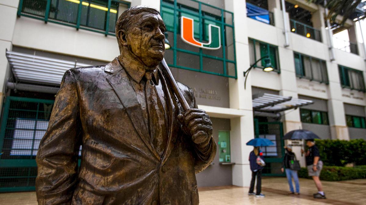 The Ron Fraser statue stands soaked as umbrella toting fans begin their departure after learning the University of Miami baseball team was forced to postpone the first round of the NCAA Division I Baseball Tournament against Canisius College due to rain at Alex Rodriguez Park at Mark Light Field in Coral Gables, Florida, on Friday, June 3, 2022. The Coral Gables Regional has been moved to Saturday, June 4th.