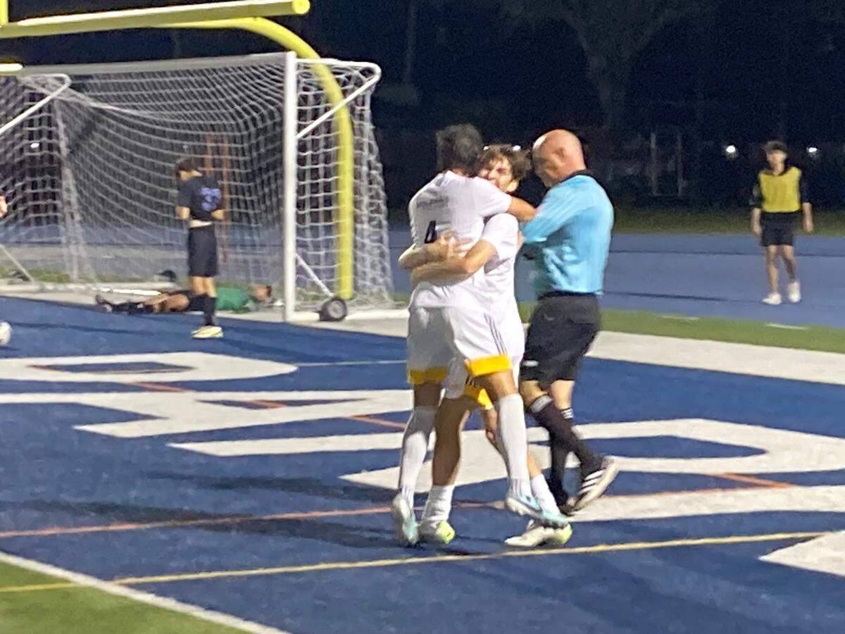 Downtown Doral’s Siul Rueda hugs a teammate following his goal on Wednesday night in the Region 4-3A boys’ soccer final at Tropical Park.