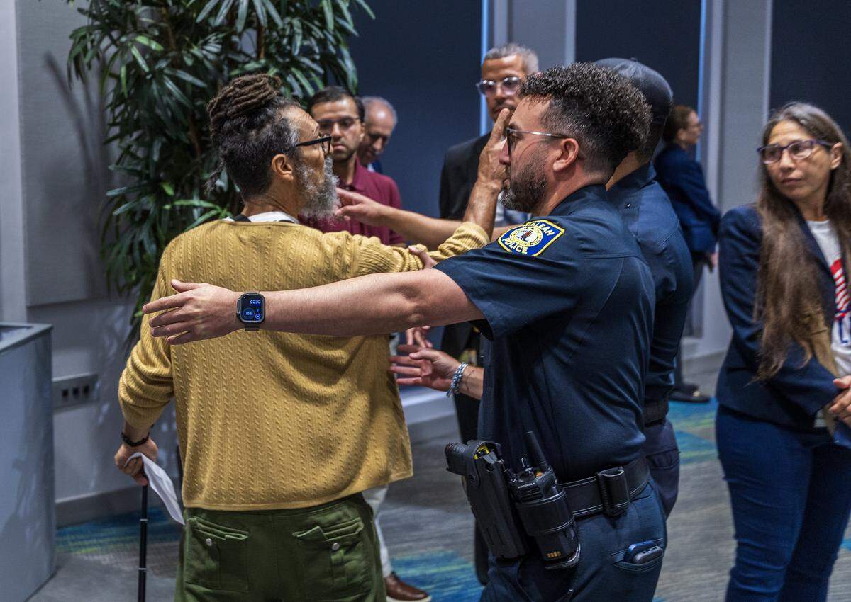 Hialeah Police Officers escorted out an unidentified attendee during a special board meeting, held by the Miami Dade College Board of Trustees to discuss the potential real estate transactions including the authorization to convey a +/-2.63 acre surface parking lot at the Wolfson Campus for further conveyance for a Presidential Library for Donald J. Trump, celebrated at the MDC Hialeah Campus, on Wednesday, December 02 , 2025.