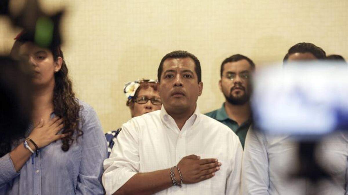 Nicaraguan opposition activist Felix Maradiaga, center, stands at attention during the national anthem at a 2019 press conference in Managua.