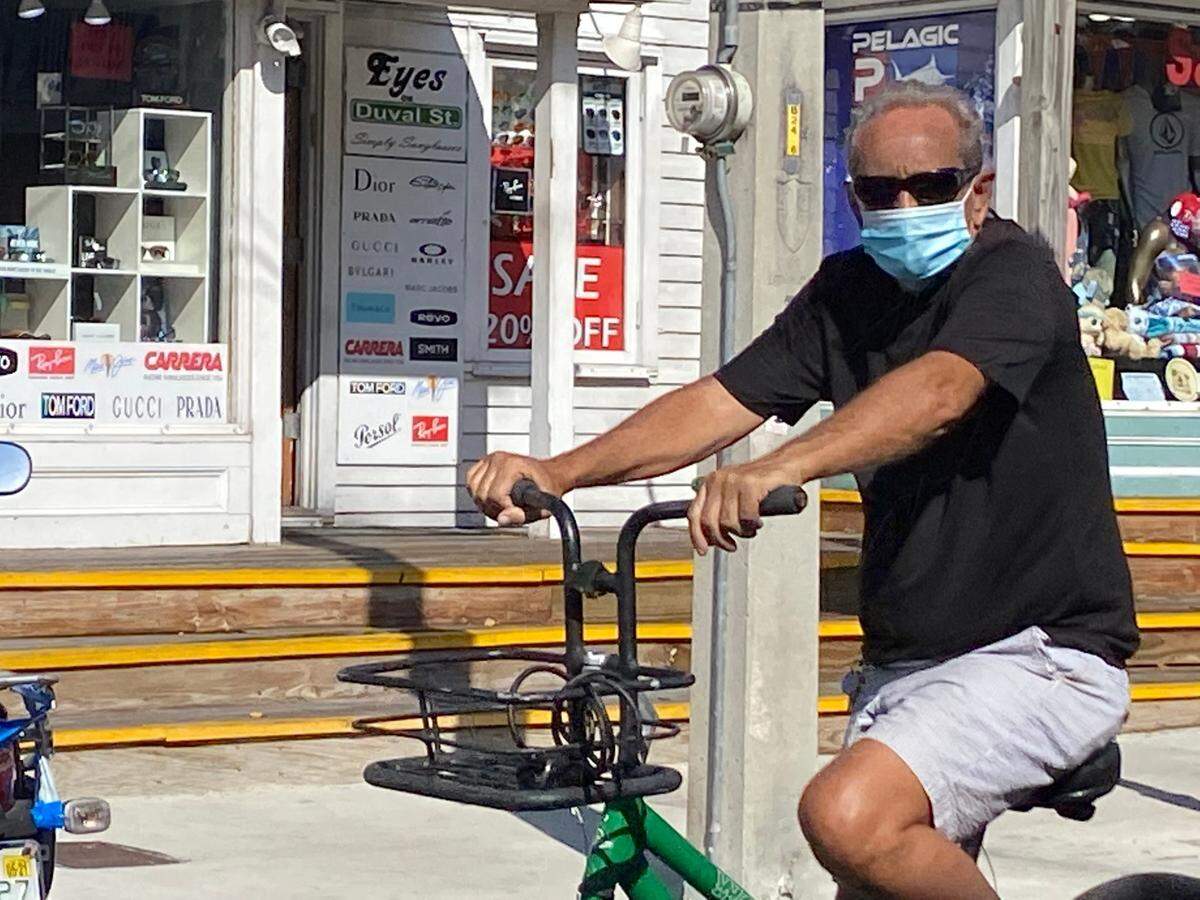 A bicycle rider masks up during a ride up Duval Street in Key West on July 16, 2020.