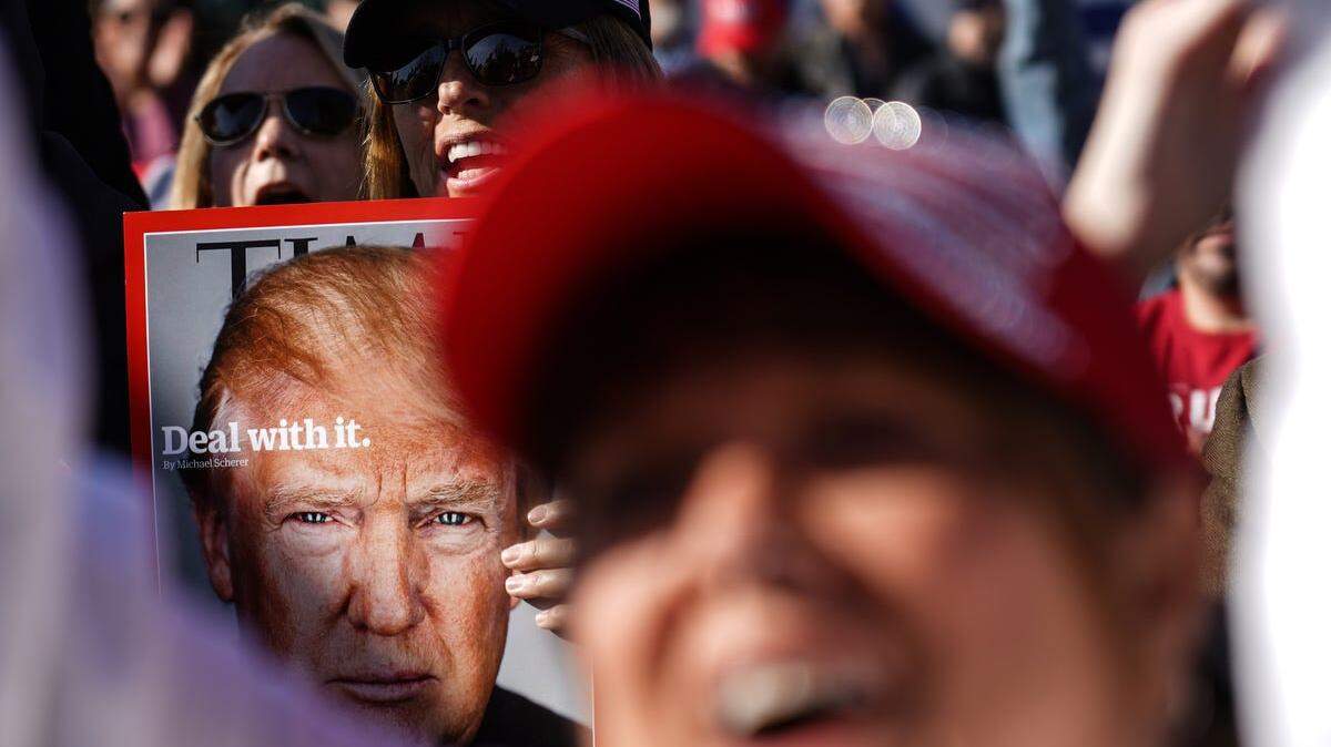 A woman holds a Time magazine cover of President Trump while cheering on a speaker during a Detroit rally in support of the president on Nov 6, 2020.
