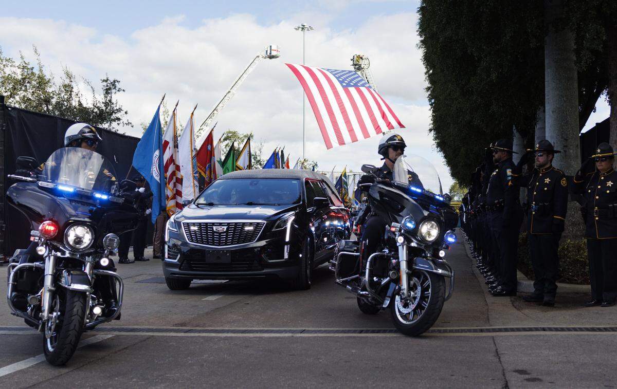 The procession, including the hearse, drives passed the street lined with honor guard for a funeral service for Miami Beach Police Sergeant David Cajuso on Wednesday, Nov. 12, 2025, at the Hard Rock Stadium in Miami Gardens, Fla.
