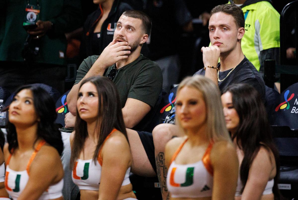 Jake Ferguson, NFL tight end, left, and Carson Beck, college football quarterback, watch their girlfriends, the Cavinder twins, play during the second quarter of a game on Thursday, Jan. 30, 2025, at Watsco Center in Coral Gables, FlA.