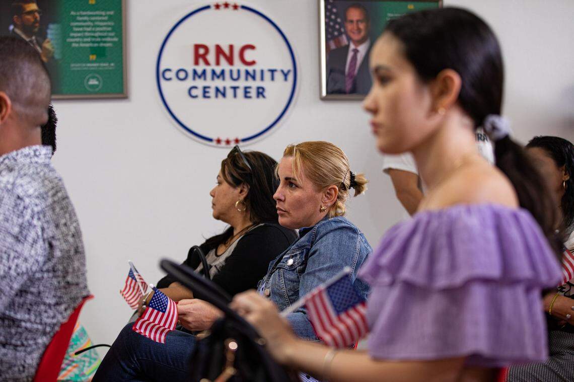 Maigrey Guerra Perez, center, listens as Hispanic Communications Director of the Republican National Committee Jaime Florez speaks to graduates of a civics course for migrants taking the U.S. naturalization test at the RNC Hispanic Community Center in Doral, Florida, on Tuesday, Oct. 4, 2022.