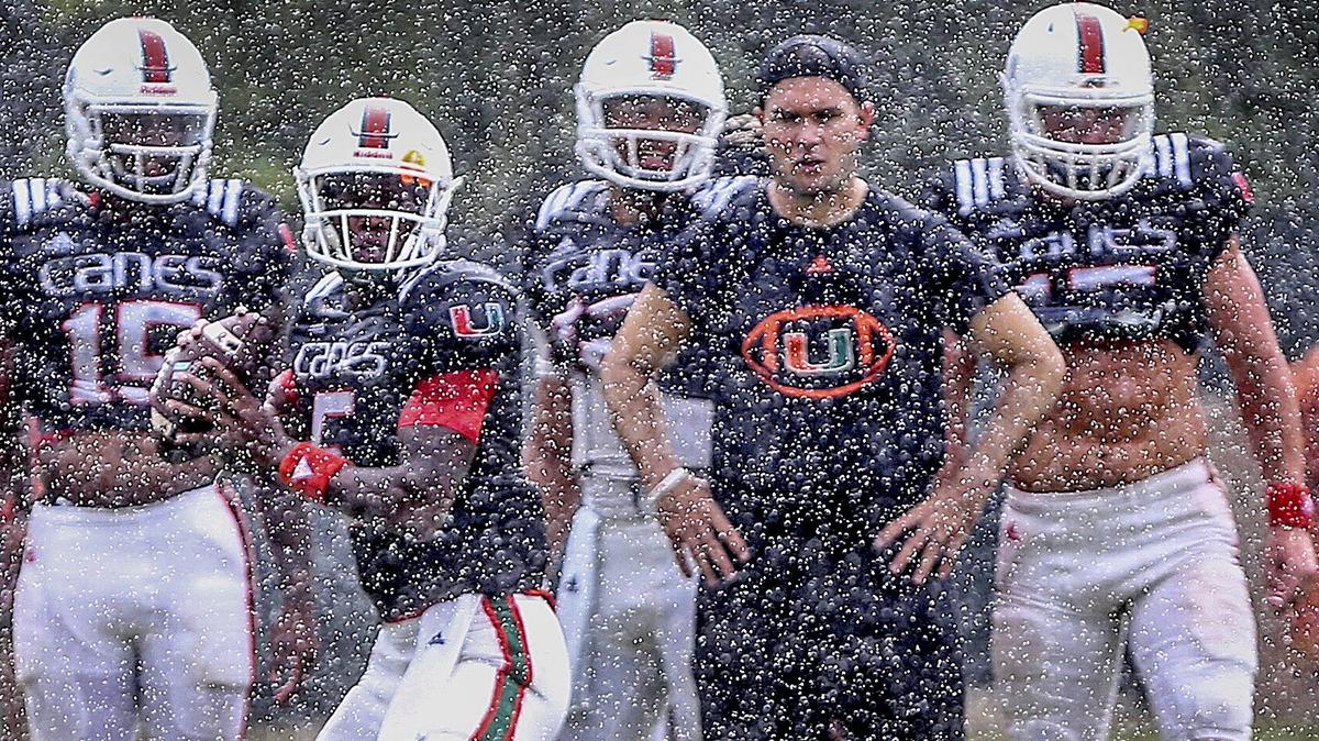 University of Miami quarterbacks coach Jon Richt watches during a rain shower as redshirt freshman backup quarterback N’Kosi Perry passes, with freshman quarterback Jarren Williams (left), starter Malik Rosier (center) and redshirt freshman Cade Weldon observing at Greentree Field on Monday, August 13, 2018.