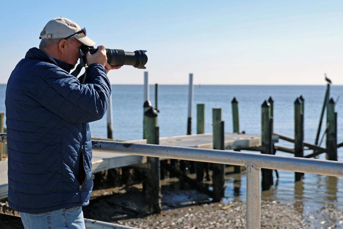 Charlie Andaloro, 70, of Greenwich, N.J., aims his camera towards a seagull perched on a post on Jan. 14, 2025, in Cedar Key, Fla. He thinks Trump’s idea to rename the Gulf is “a troll.”