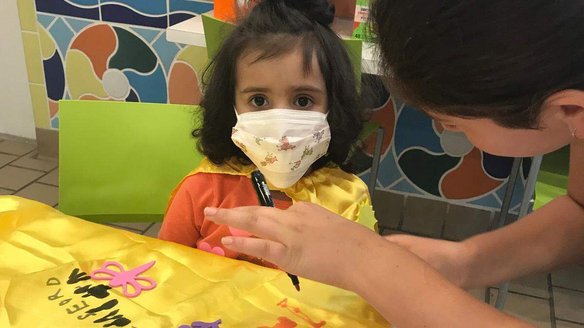 Daisy Stein, 12, sister of Capes for Courage Founder Jade Stein, 13, helps a patient design a cape at the Ronald McDonald House.