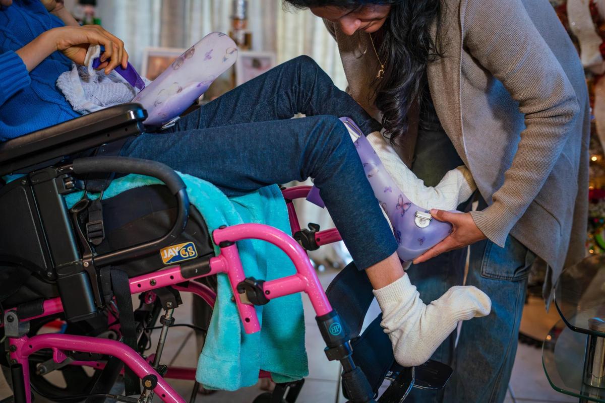 Damaris Delgado puts foot orthotics on her daughter, Standarlyn Muñoz Delgado.