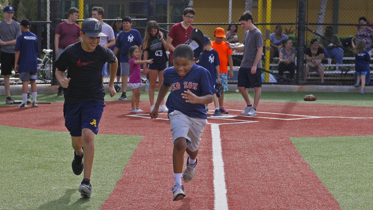 Baseball Buddies’ Noah Katzman, 14, runs with Garth Fowler, 9, right, who has autism, as they participate in North Miami Beach Little League Baseball Buddies program at Pelican Park in Sunny Isles Beach on Sunday, Nov. 4, 2018.