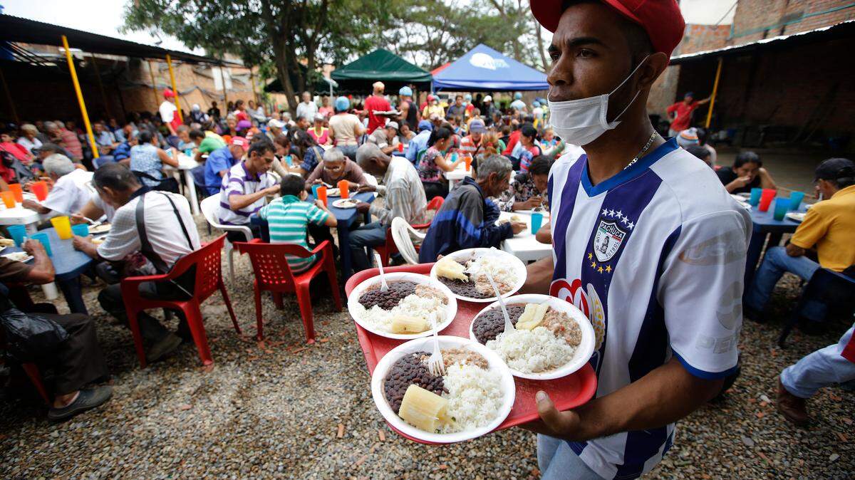 A volunteer at the “Divina Providencia” migrant shelter distributes lunch to Venezuelan migrants, in Cúcuta, Colombia, in February, 2018. The food is cooked in several large vats and the diocese says it offers an average of 1,000 meals a day.