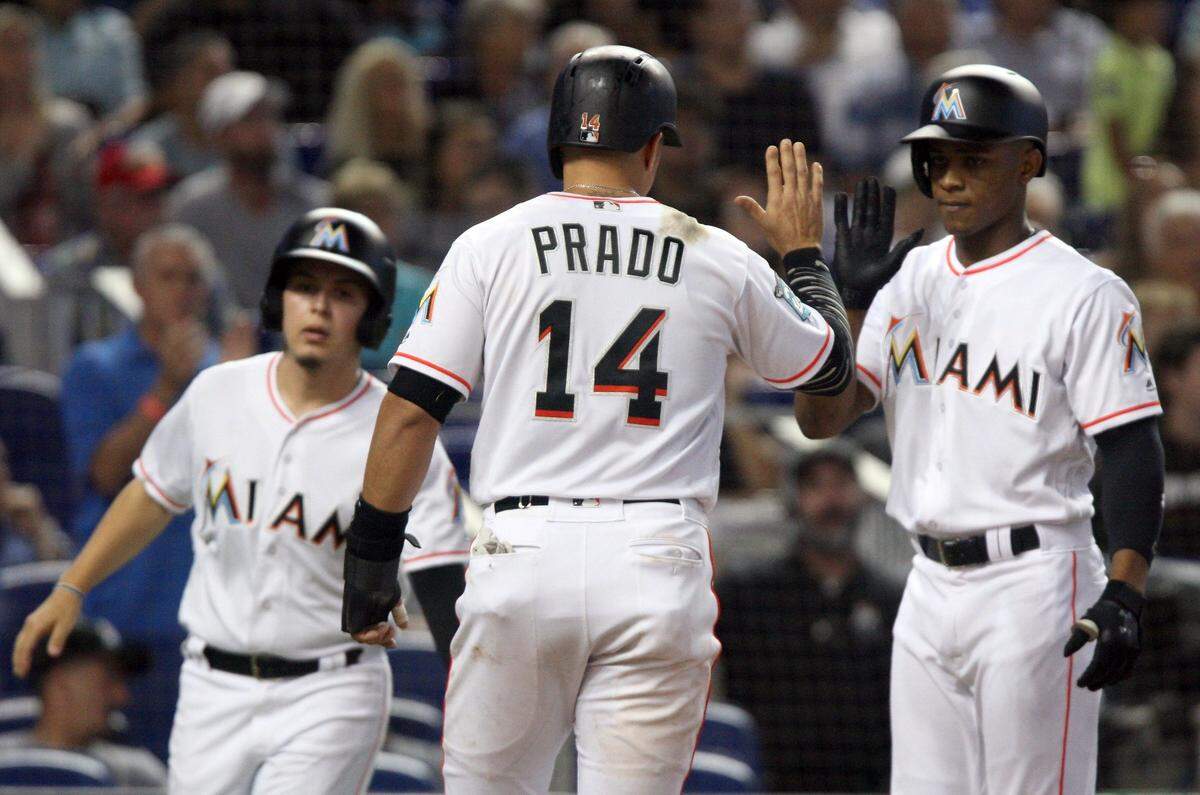 Martin Prado exchange fives with teammate Magneuris Sierra, right, as he scores 1 of the 3 runs as the Marlins bats got hot at the bottom of the 5th inning during the Marlins vs National baseball game inside Marlins Park, Miami, Florida on Sunday, July 29, 2018. 