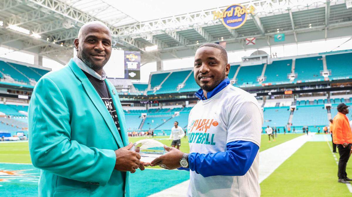 Eddie Frasier (right) receives the Miami Dolphins’ coach of the year award after leading Dillard to an undefeated regular season in 2019.