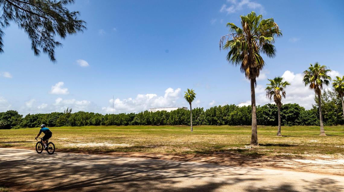 A cyclist makes his way past a plot of land between the Virginia Key Outdoor Center and the mountain bike course at North Point, adjacent to the sewage treatment plant in Virginia Key on July 28, 2022. Miami has been studying the possibility of taking people experiencing homelessness off the streets and moving them to a city-sponsored encampment on this site in Virginia Key.