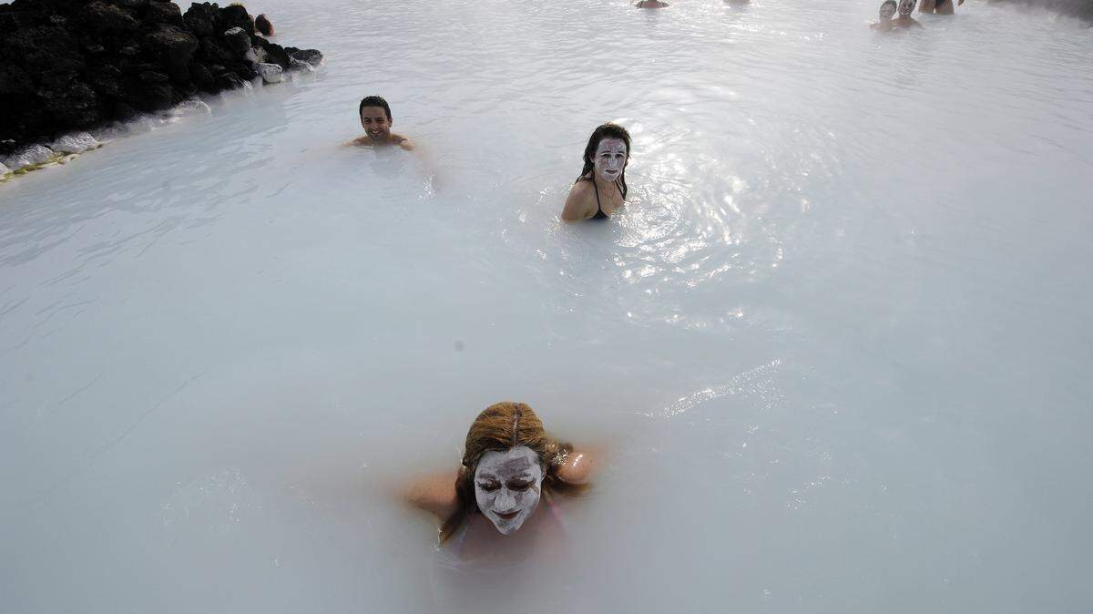 Tourists stand in the Blue Lagoon outside Reykjavik on 26 April, 2009. The Blue Lagoon’s blue and green waters come from natural hot water springs flowing through rocks of lava.