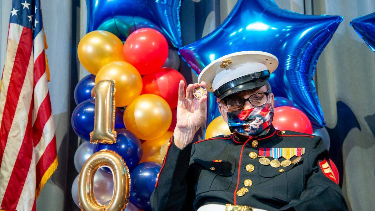 World War II Marine Corps Veteran and North Miami Beach resident Nunzio “Baron” Capizzi holds up his 100th birthday pin given to him at a party hosted by the City of North Miami Beach. He celebrated his centennial birthday with his daughters, friends, and public officials.