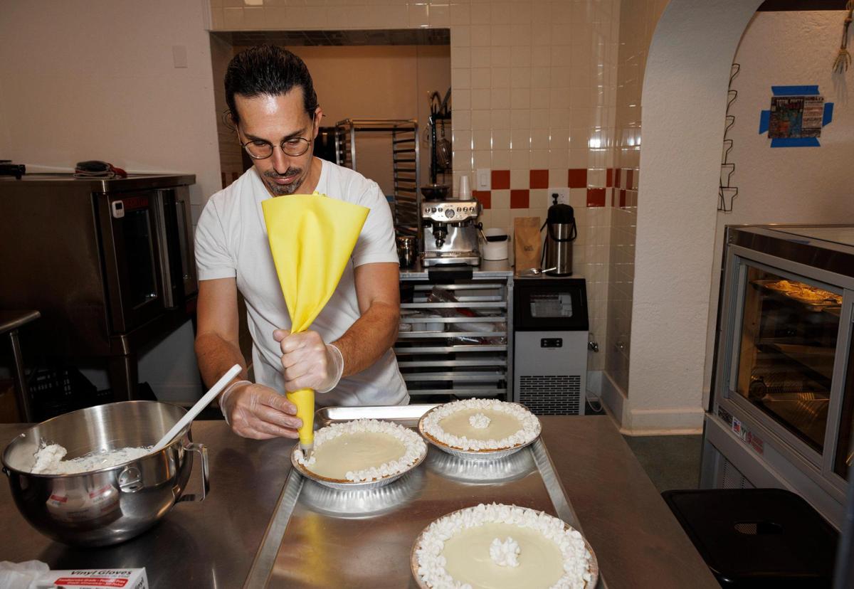 Joshua Abril tops Key lime pies with whipped cream at his new shop.