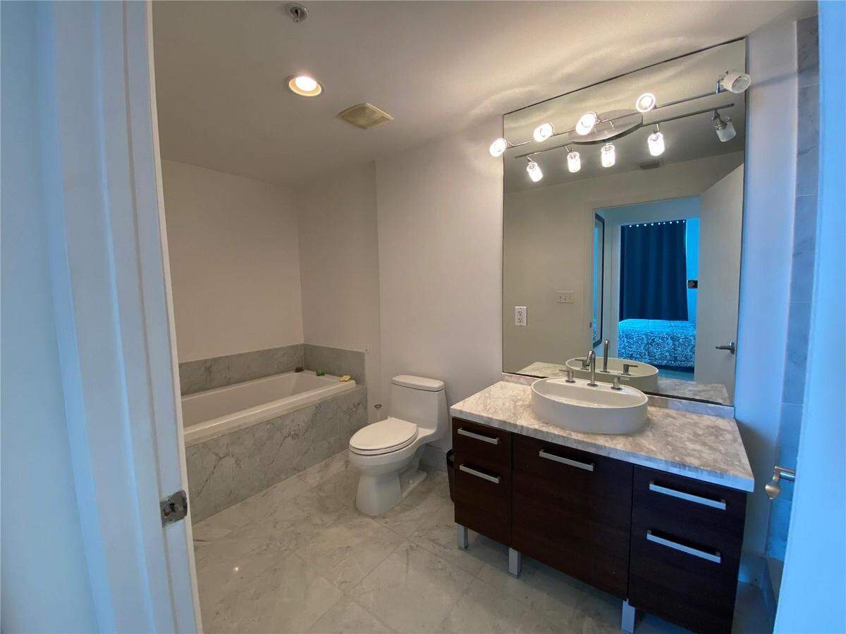The apartment has both a bathtub, pictured on the left, and a walk-in shower in the bathroom.