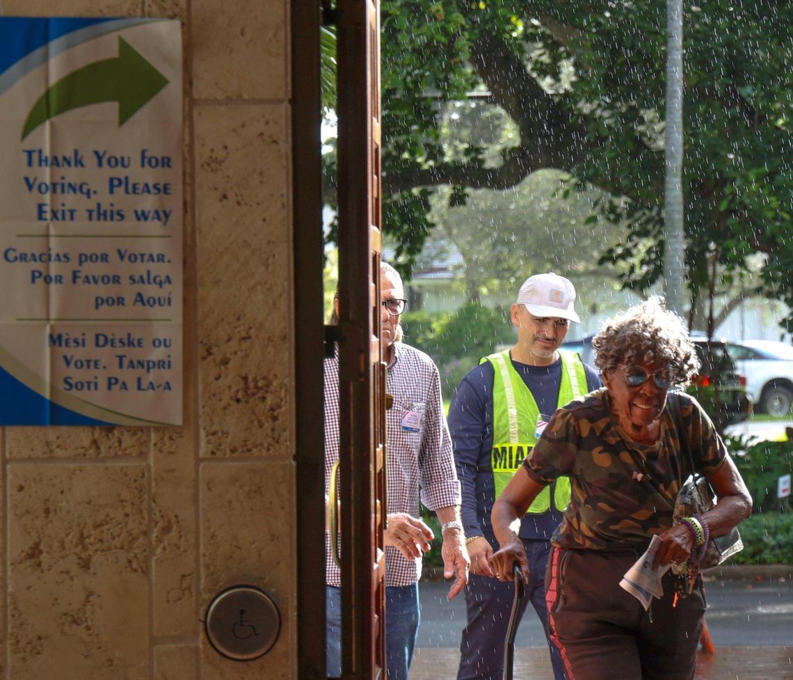 Voters escape a sun shower as while arriving at the Coral Gables Library to cast their vote during early voting on Monday, October 21, 2024, in Coral Gables, Florida.