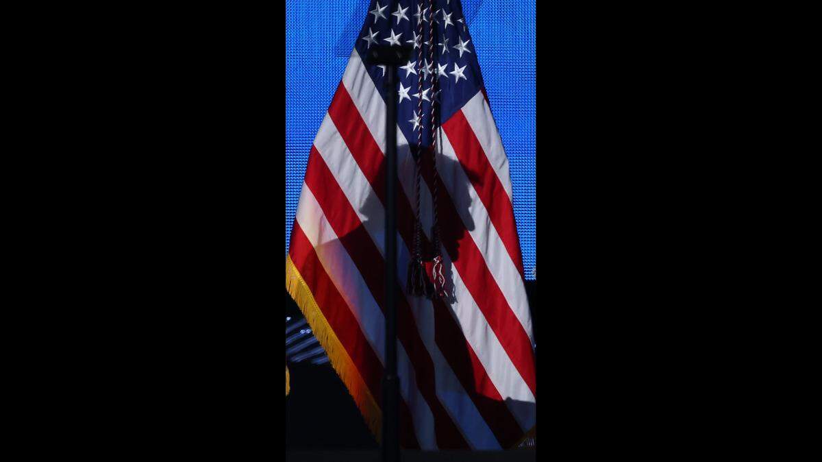 President Donald J. Trump’s shadow is cast on the American flag as he walks on stage to address the attendees of the American Business Forum at the Kaseya Center in Miami, Florida on Wednesday, November 5, 2025.