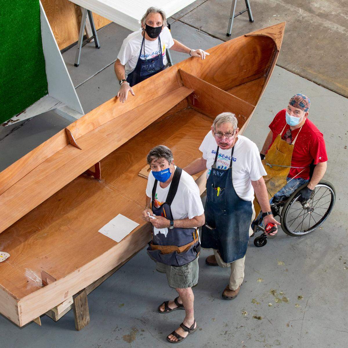 Veteran volunteer instructors Michael “Mike” Rubin, 69, top left, Simon “Si” Bloom, 81, bottom left, Larry Leitner, 75, bottom center, and Francis “Winky” Weinke, 71, bottom right, gather around the sailboat to take measurements during class for a vocational program in which students learn about boat maintenance, restoration, and repair at Shake-A-Leg Miami in Coconut Grove, Florida, on Wednesday, Feb., 10, 2021.