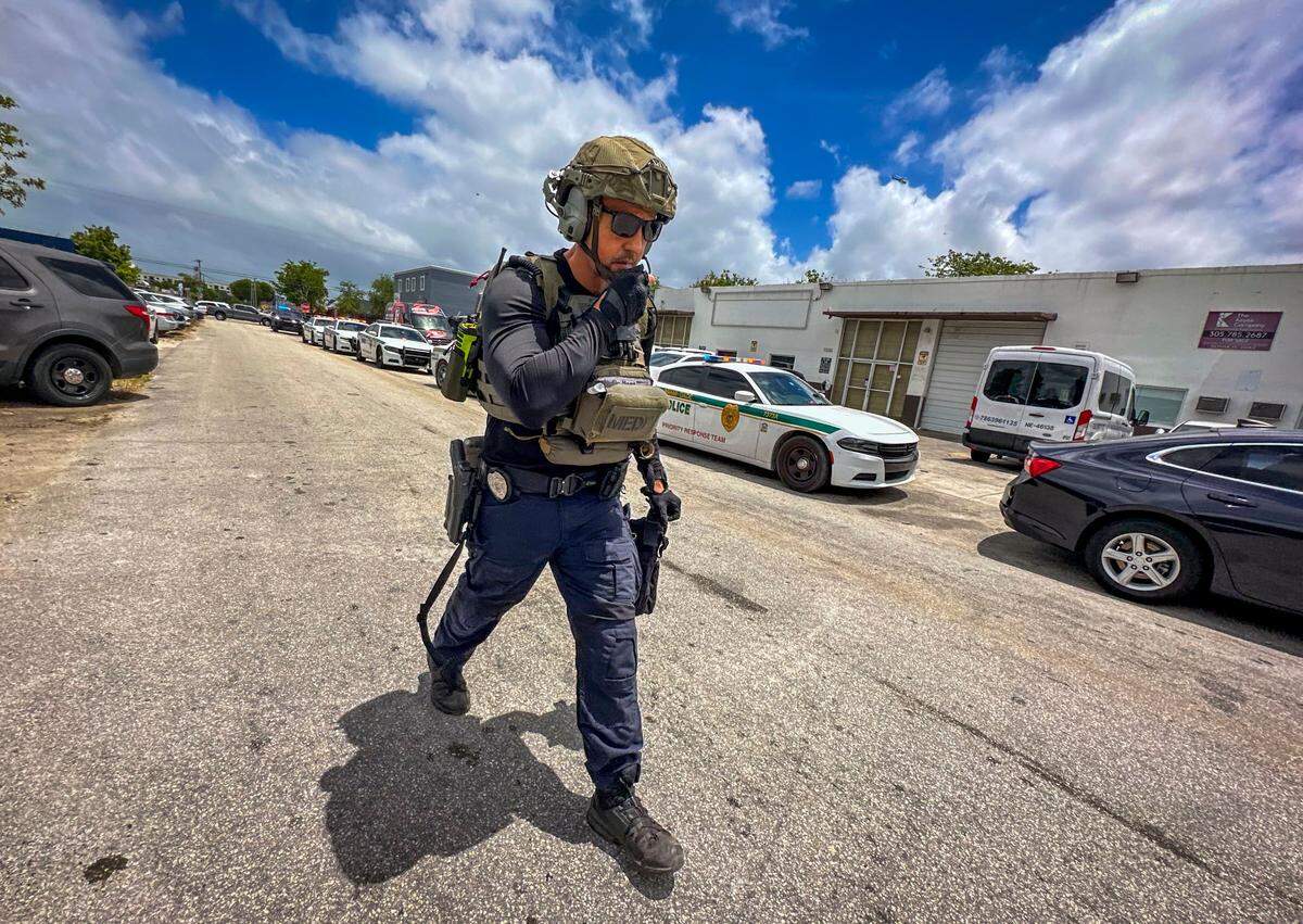 Armed law enforcement officers walks by as Miami-Dade Sheriff’s Office investigates a shooting near Southwest 75th Avenue and 45th Street, in the warehouse district south of Bird Road.