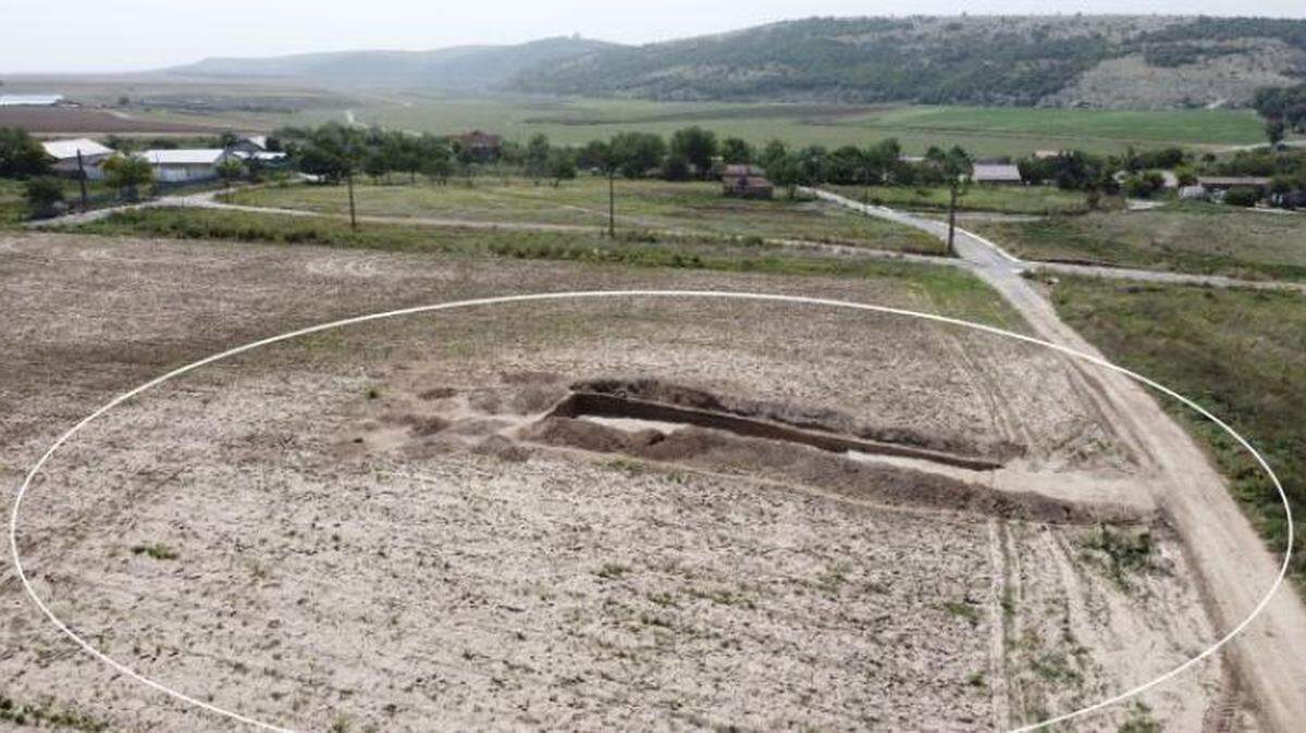 Archaeologists found two ancient Roman graves at a burial mound: a looted grave with a wolf skull and an untouched skeleton with money, photos show.