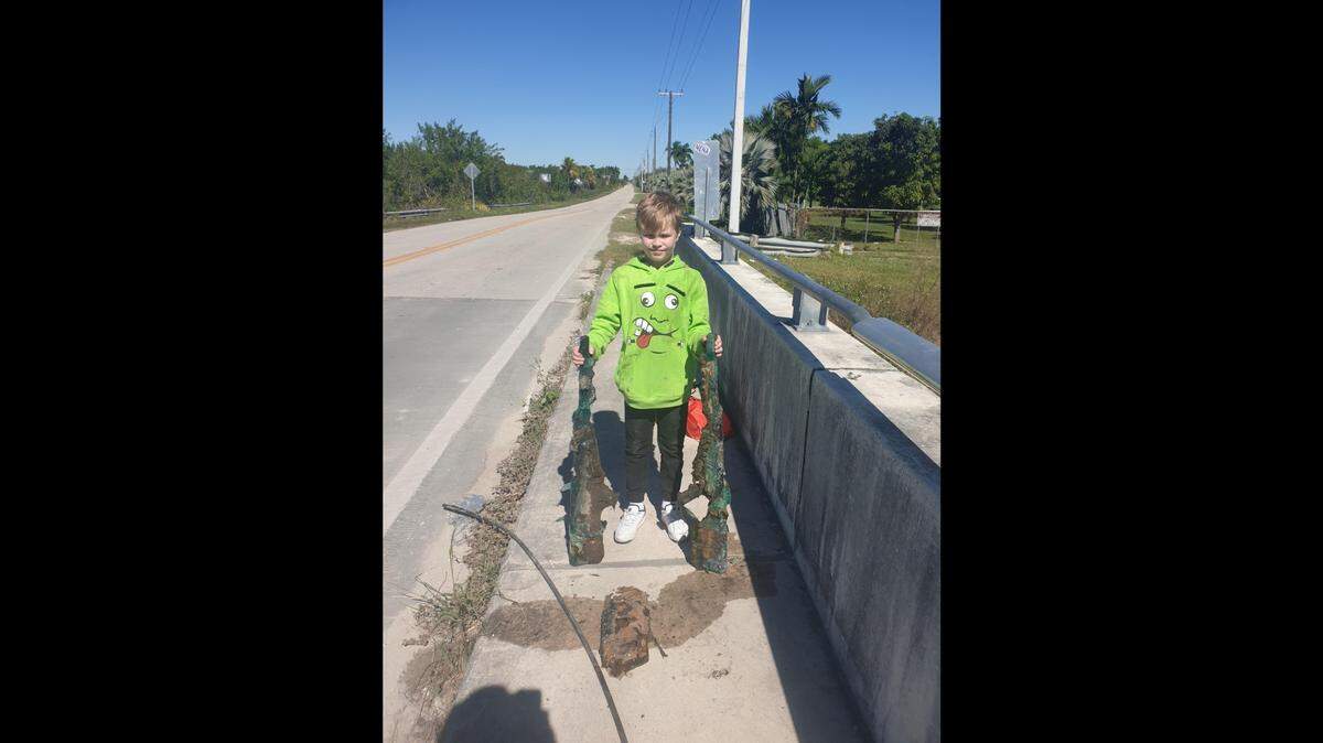 Allen Cadwalader, 11, holds the lower receivers of two .50-caliber sniper rifles he and his grandfather found in a Miami-Dade County canal Sunday, Jan. 30, 2022.