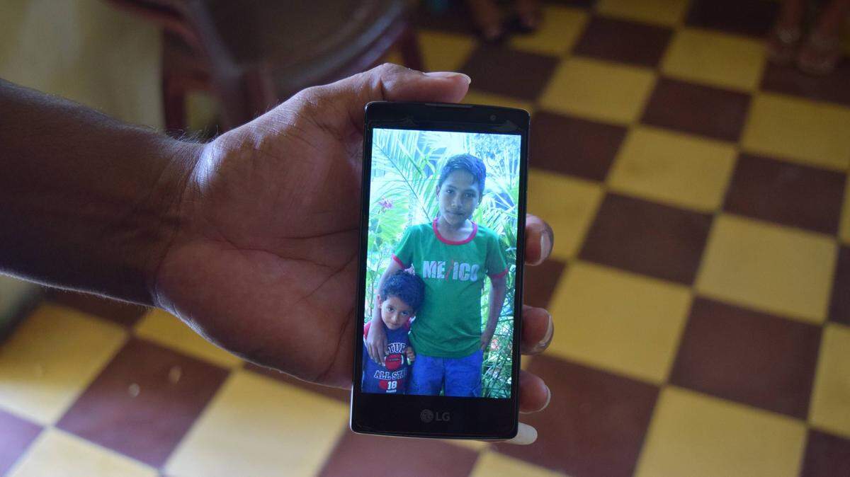 Jose Caceres holds up a picture of his sons in Yoro, Honduras. Brayan, 11, right, was separated from his father two months ago as they tried to enter the United States. Caceres was deported back to Honduras and Brayan is in a shelter in Maryland.