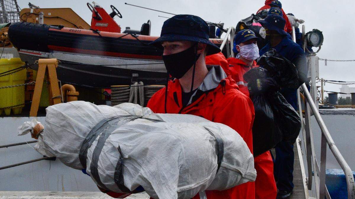 Coast Guard Cutter Legare crew members offload about 3,900 pounds of marijuana in the rain at Port Everglades, Florida.