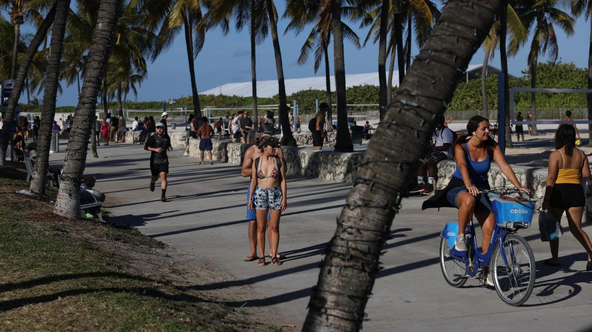 People walk along the sidewalk at Miami Beach during spring break on Sunday, March 26, 2023.