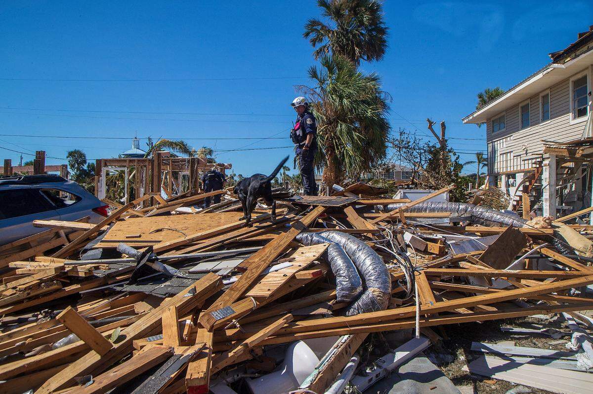 Members of the search and rescue team from Miami including Pasco, a black Labrador retriever, search the rubble for missing persons at Fort Myers Beach, two days after Hurricane Ian hit Florida’s west coast as a Category 4 storm.