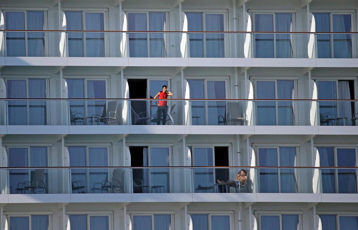 Crew members go out on their balconies on the Norwegian Encore at PortMiami on Thursday, March 26, 2020. One day after leaving the ship on March 24, a crew member tested positive for COVID-19. Those left on board still cram into a crowded crew mess hall to eat without social distancing, and say they don’t have masks and gloves.