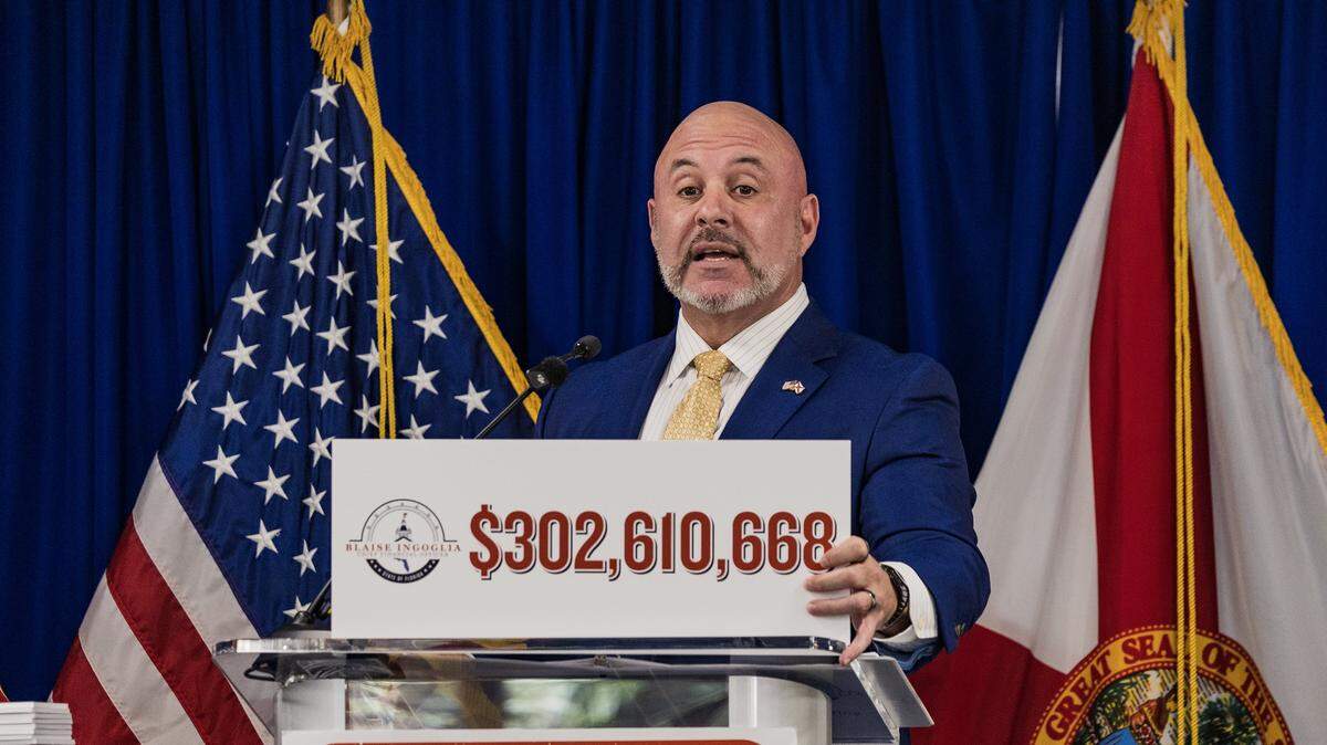 Florida CFO Blaise Ingoglia holds a sign showing the amount of money he claims that Miami_Dade is overspending in its 2025 budget, as he speaks about the government accountability and wasteful spending in Miami Dade County, during a press conference at Florida International University's (FIU) Biscayne Bay Campus, on Thursday October 30, 2025.