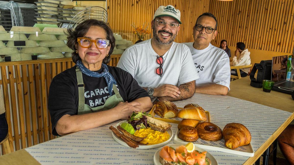Jesús Brazón, en el centro, con sus padres, Scarlet Rojas y Manuel Brazón, y algunos de los panes y platos disponibles en su segunda Caracas Bakery en Miami. Manuel y Jesús Brazón son semifinalistas para el Premio James Beard 2024 al mejor pastelero o panadero.