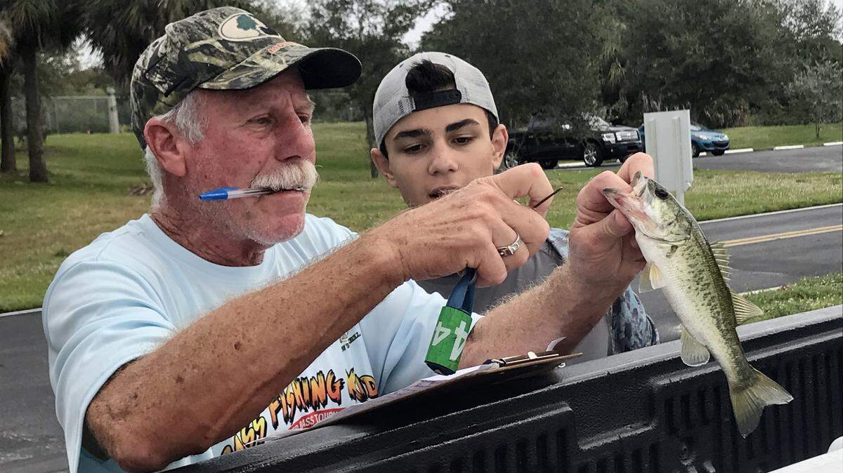 Bass Fishing Kids co-founder Bob Newland with a bass caught by Christos Andrianopoulos at a tournament earlier this month at Quiet Waters Park in Deerfield Beach.