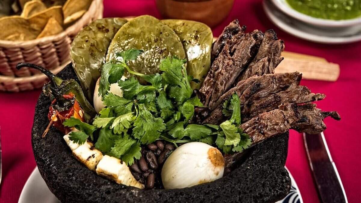 Steak molcajete served with grilled cheese, nopal (prickly pear), grilled onions, peppers and black beans at the Fonda Mexicana restaurant in Mexico City on September 19, 2016. (Photo by OMAR TORRES / AFP via Getty Images)