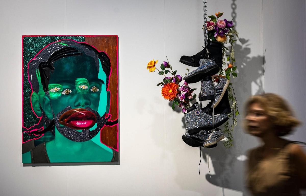 Devan Shimoyama’s “Self Portrait with Braids, Doubled,” 2022, left and “Before the Storm,” 2022, a sculpture made with Timberland boots, rhinestones, silk flowers, epoxy resin and a chain hang on the wall at the Miami Beach Convention Center during the Art Basel VIP opening day.