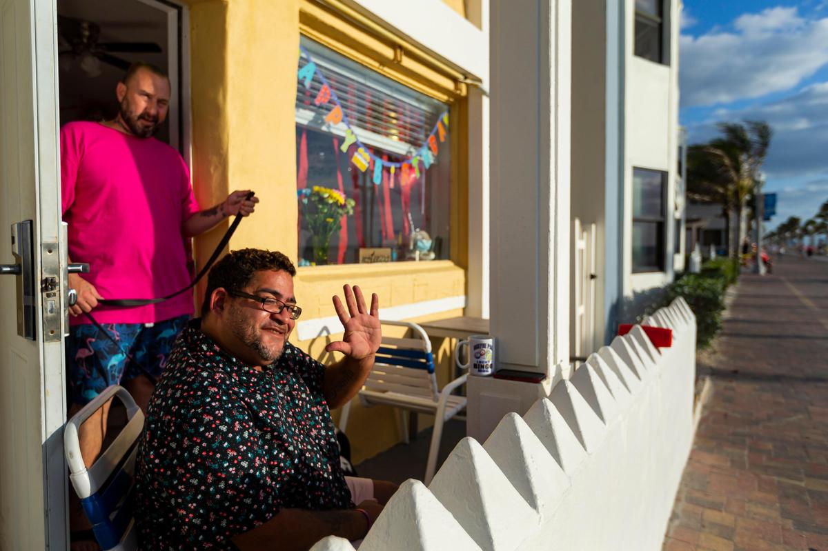 Rolando Pabon enjoys a drink with Joseph Katzman while celebrating his 41st birthday as beachgoers make their way down Hollywood Beach Broadwalk.