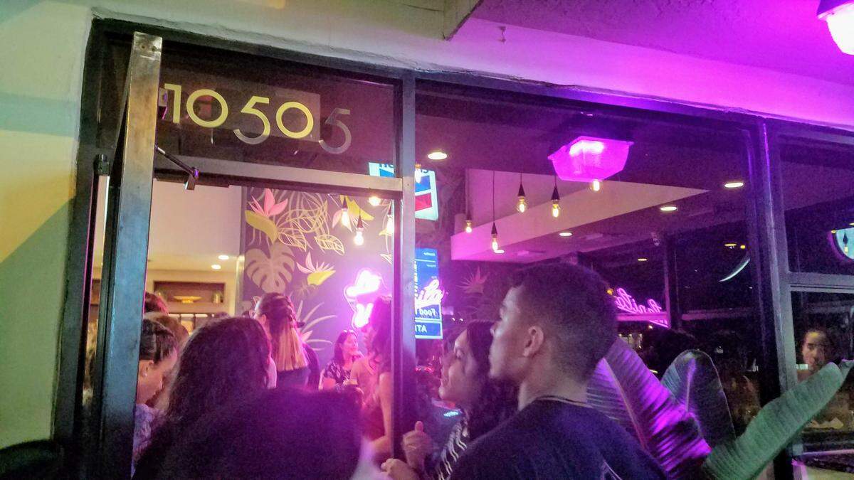 Patient customers peer into Dos Croquetas after waiting for two hours in line to order.