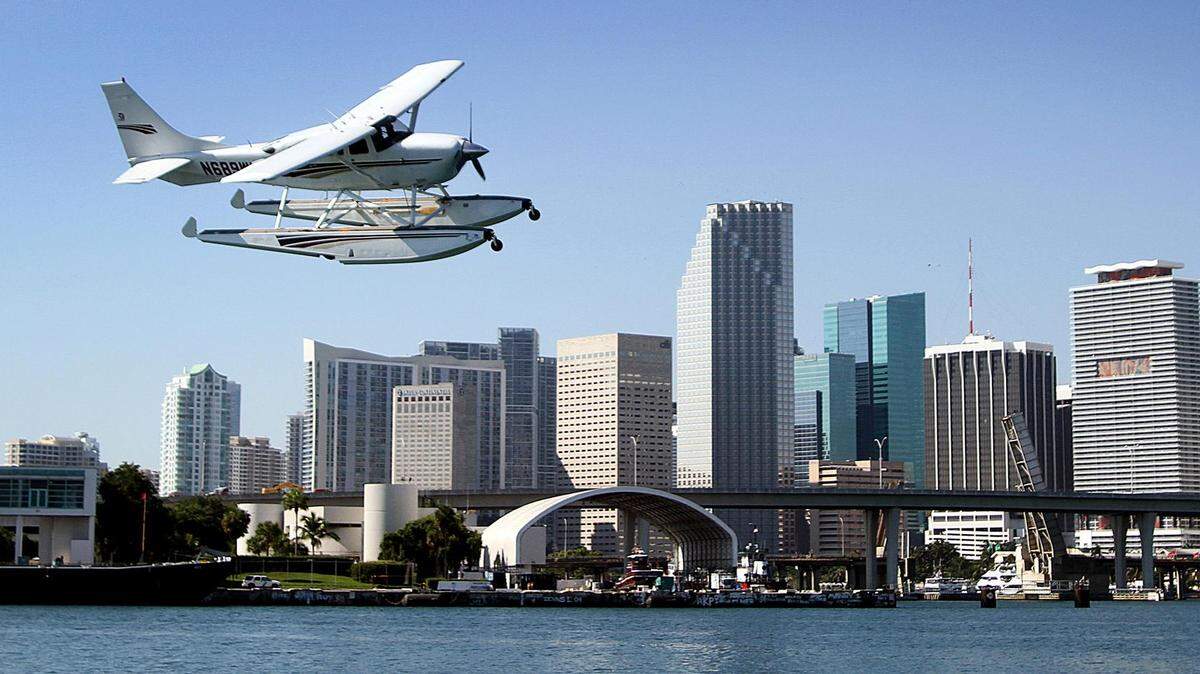 A Cessna 206 amphibious seaplane from the Miami Seaplane Base on Watson Island takes off in front of downtown Miami.