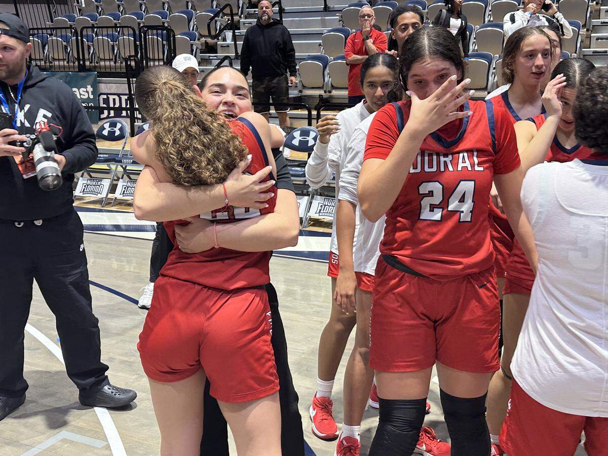Doral Academy coach Daniela Barrios hugs guard Ashley Martinez on the left while Stephanie Vega (24) cries tears of joy after the Firebirds won their first state championship on Saturday at UNF Arena in Jacksonville, Fla.