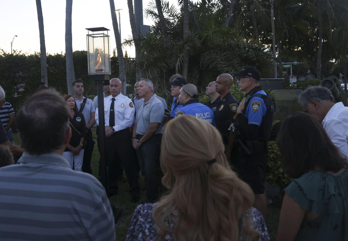 Miami Date Fire Rescue and community members gather on Wednesday, July 20, 2022, during a ceremony to extinguish the symbolic flame in front of the site where Champlain Towers South once stood in Surfside. One year ago, the last of 98 victims was recovered from the site.
