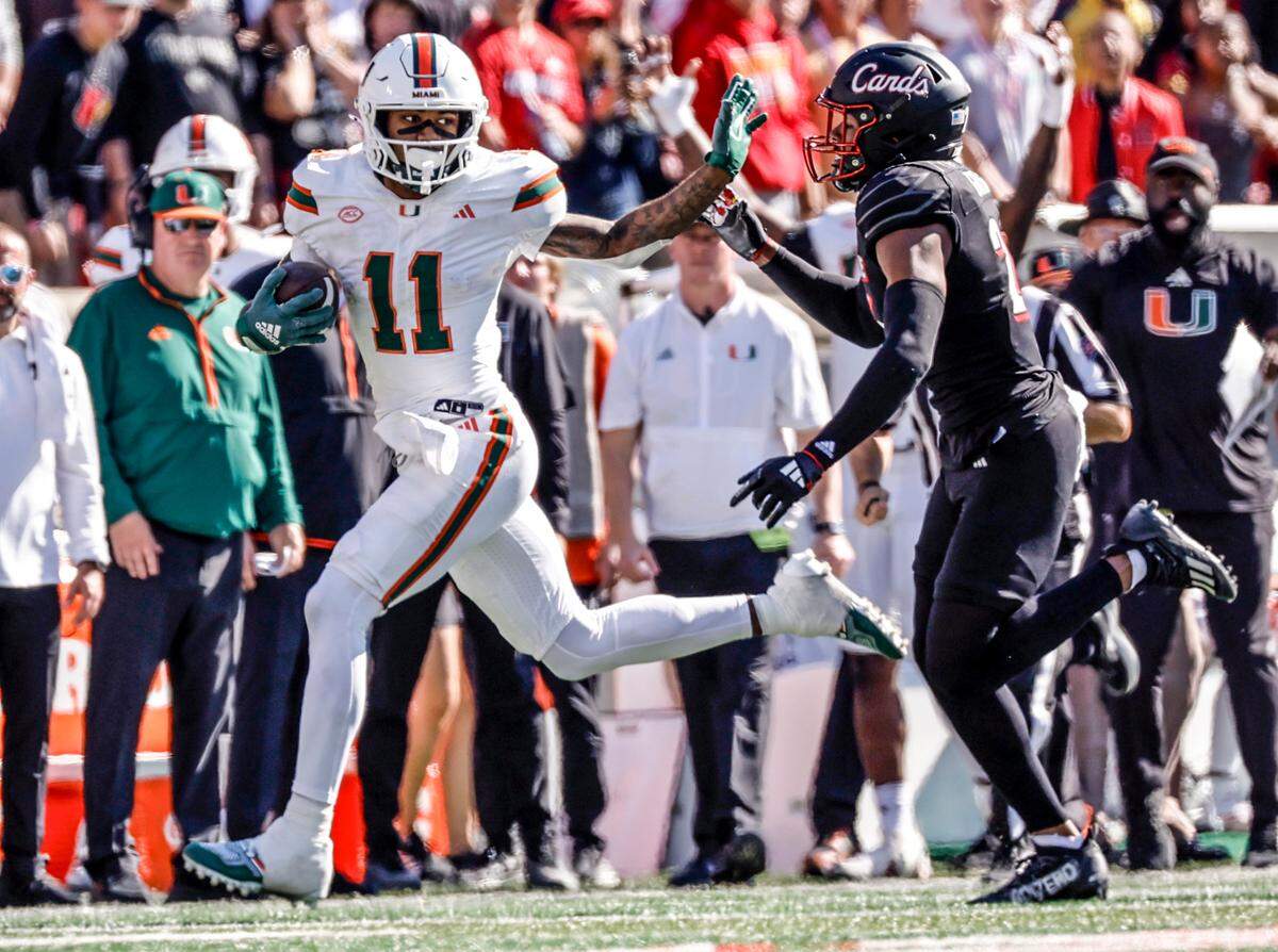 Miami Hurricanes wide receiver Samuel Brown (11) evades a tackle by Louisville Cardinals defensive back M.J. Griffin (26) in the second half during an NCAA football game at L&N Federal Credit Union Stadium in Louisville, Kentucky on Saturday, October 19, 2024.